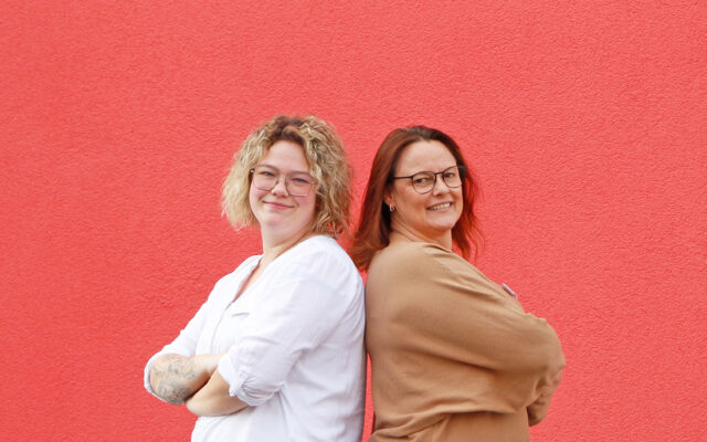 Katja Gutmann (r.) und Daniela Geißler (l.) vor einer roten Wand.