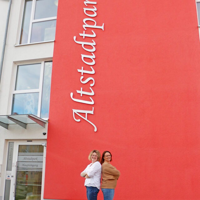 Katja Gutmann (r.) und Daniela Geißler (l.) vor dem Eingang des BRK-Altstadtparks. Im Hitnergrund der Schriftzu Altstadtpark an der Wand.